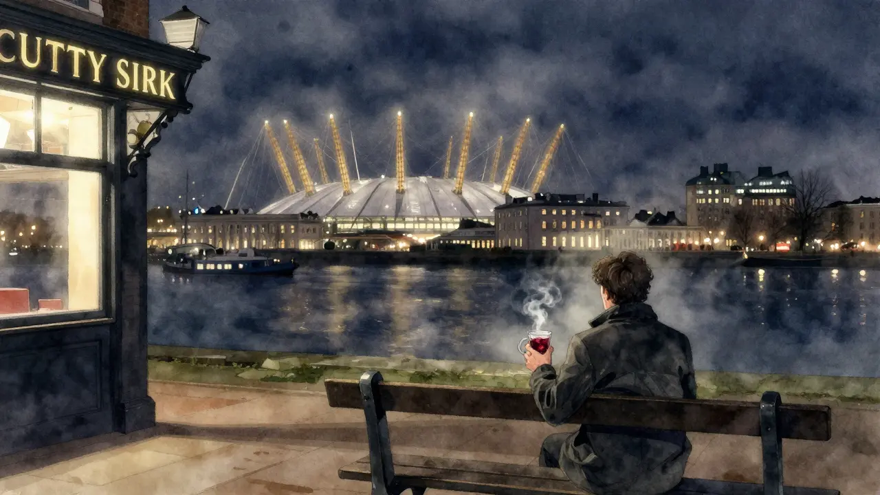 A quiet figure by the Thames at night with the O2 Arena glowing in the distance.